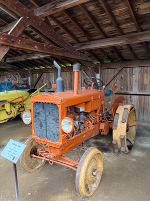 deux vieux tracteurs dans une grange, avec une pancarte devant eux
