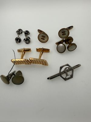 several pairs of cufflinks and a pair of cufflinks on a white surface
