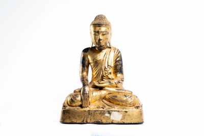 une statue en or représentant une personne assise sur un rocher