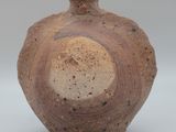 a brown vase that is sitting on a white surface