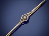 a close up of a gold and pearl tie bar on a blue background