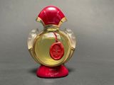 a red and gold perfume bottle with a wax seal on it