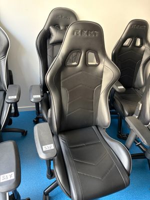 plusieurs chaises de bureau noires et grises dans une pièce recouverte d'une moquette bleue