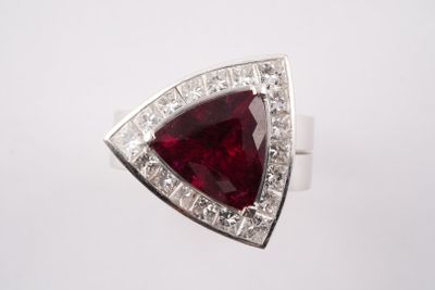 un gros plan d'une bague sertie d'une pierre rouge et de diamants