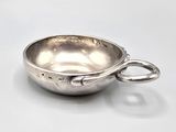 a close up of a silver bowl with a handle on a white surface