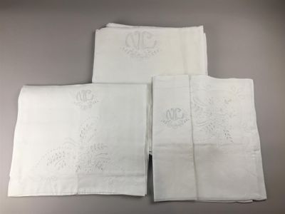 quatre pièces de linge blanc brodées, posées sur une table