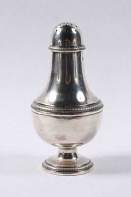 une salière ancienne en argent posée sur un socle, sur fond blanc