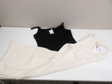 two pairs of white pants and a black tank top on a table