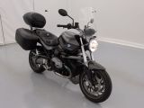 une moto noire garée dans une pièce aux murs blancs