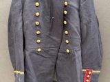 un vieux manteau militaire accroché au mur à côté d'un porte-manteau