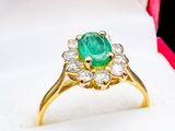 an emerald and diamond ring in a red box on a white surface
