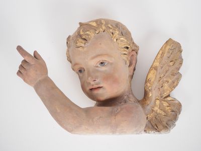 une statue représentant un ange qui montre quelque chose du doigt sur le mur