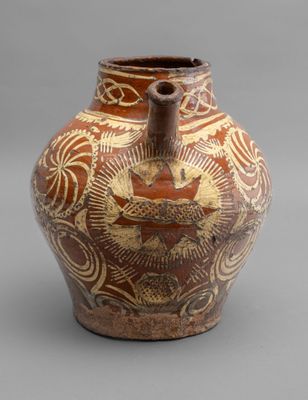 a brown vase with a design on it on a gray surface