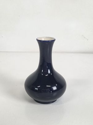 un petit vase noir posé sur une surface blanche