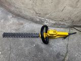 une tondeuse à gazon à fil jaune posée par terre à côté d'un mur en béton