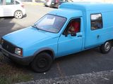 a small blue van parked on the side of the road