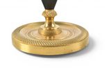 a gold candle holder with a black candle on it