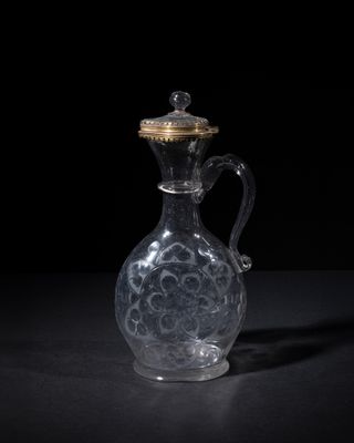 a clear glass jug with a gold lid sitting on a black surface