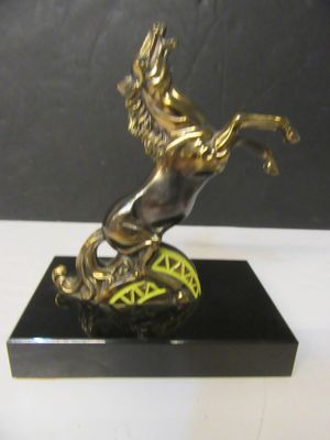 une statue en bronze représentant un cheval, posée sur un socle noir
