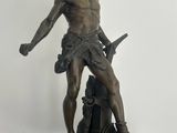 bronze statue of a man holding a sword on a black base