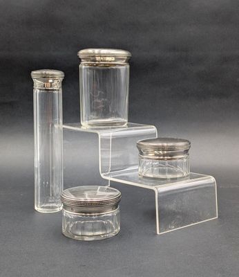 trois bocaux en verre transparent avec des couvercles argentés, posés sur une surface grise