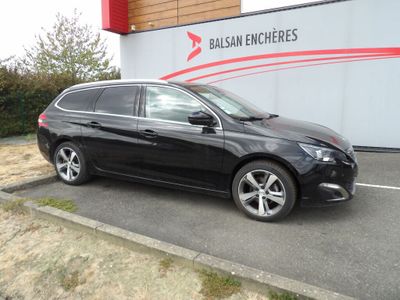 La voiture noire est garée devant un immeuble sur lequel est accrochée une pancarte.