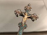 une croix en argent surmontée d'un crucifix, posée sur une table en verre