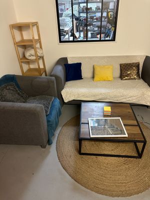 un salon avec un canapé, un fauteuil, une table basse et une fenêtre