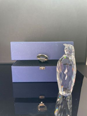 un flacon de parfum en verre transparent posé sur une table, à côté d'une boîte violette