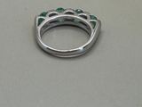 a close up of a silver ring with green stones on it