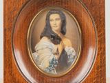 une vieille photo d'une femme en robe bleue, dans un cadre en bois