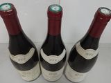three bottles of red wine are lined up on a white surface
