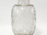 un vase en verre transparent posé sur une surface blanche, avec un fond blanc
