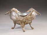 an ornate silver bowl with a bird shaped handle on a stand