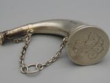 une vieille pipe en argent entourée d'une chaîne, posée sur une surface grise