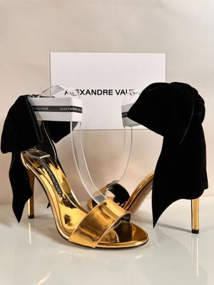 pair of black and gold high heeled shoes with a black bow tie