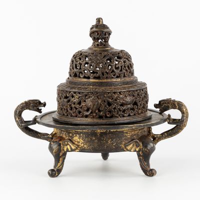 une boîte à encens en bronze richement décorée, munie d'un couvercle et posée sur un socle