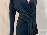 La robe est noire, elle a des manches longues et un décolleté en V.
