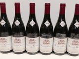 six bouteilles de vin sont alignées sur une table