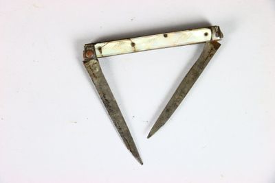 une vieille paire de ciseaux posée sur une surface blanche