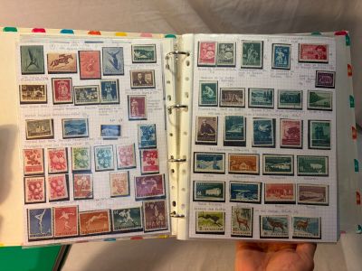 Quelqu'un tient un livre sur lequel sont collés de nombreux timbres.