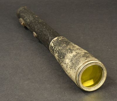 a metal pipe with a yellow liquid in it on a table