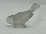 a glass bird that is sitting on a white surface
