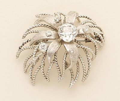 a silver brooch with a flower and leaves on it
