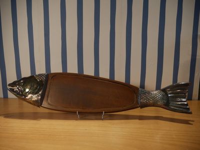 un poisson en métal posé sur une planche en bois posée sur une table
