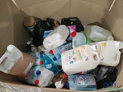une boîte en carton remplie de bouteilles et de flacons de produits d'entretien