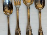 cinq cuillères en argent et une fourchette sont alignées sur une table