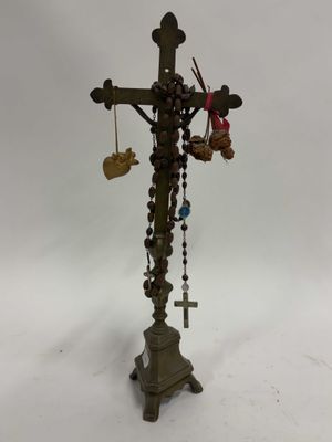 une vieille croix à laquelle pendent, sur le côté, un tas de perles