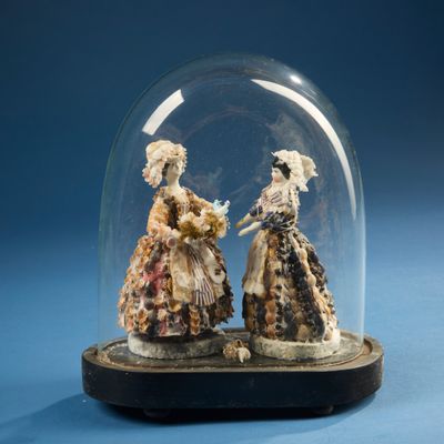 deux figurines posées sous une cloche en verre sur une table