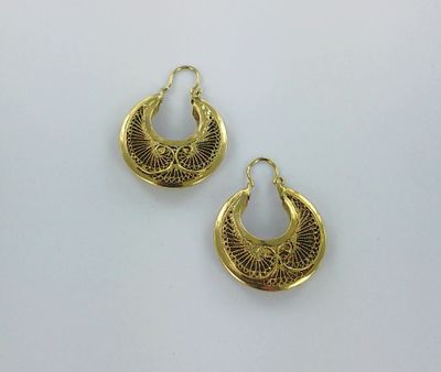 une paire de boucles d'oreilles dorées posées sur une surface blanche